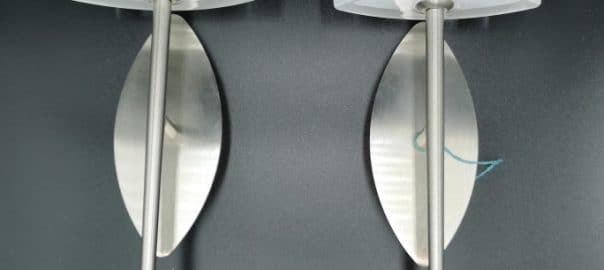 Coppia di appliques moderne in vetro curvo e metallo satinato, design elegante e funzionale.