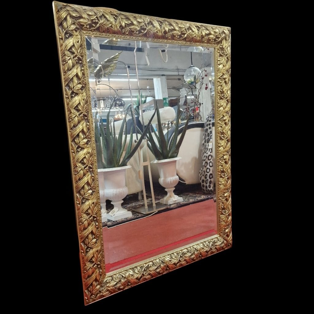Specchiera lavorata in legno dorato con cornice intagliata e specchio bisellato