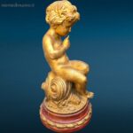 Puttino dorato in legno con base rossa laccata, oggetto decorativo pregiato