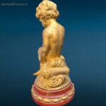 Puttino dorato in legno con base rossa laccata, oggetto decorativo pregiato