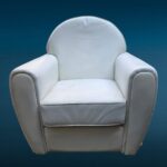Poltrona in similpelle bianca con design iconico e segni del tempo