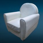 Poltrona in similpelle bianca con design iconico e segni del tempo