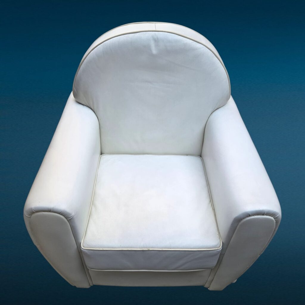 Poltrona in similpelle bianca con design iconico e segni del tempo