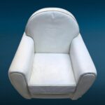 Poltrona in similpelle bianca con design iconico e segni del tempo