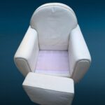 Poltrona in similpelle bianca con design iconico e segni del tempo