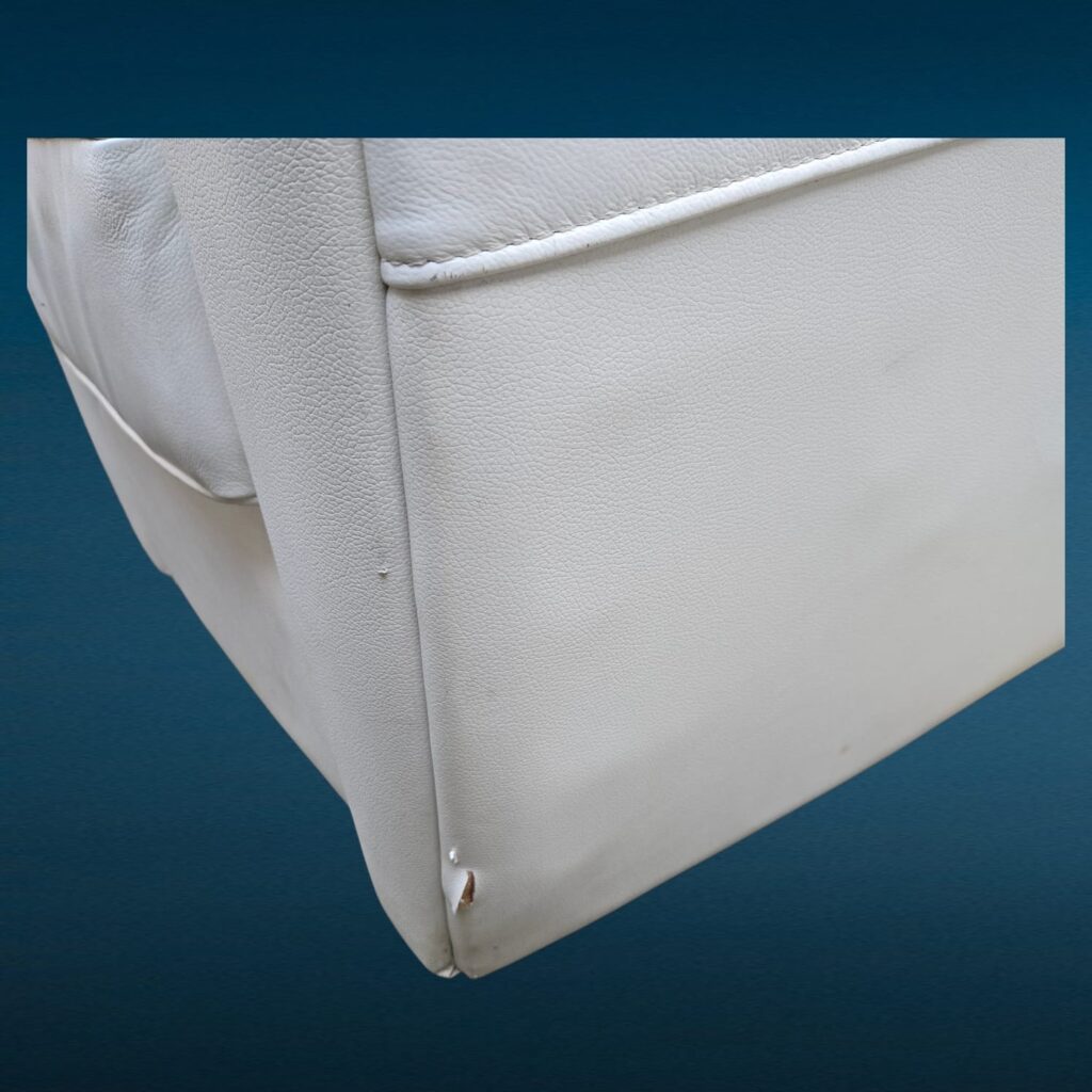 Poltrona in similpelle bianca con design iconico e segni del tempo