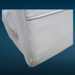 Poltrona in similpelle bianca con design iconico e segni del tempo